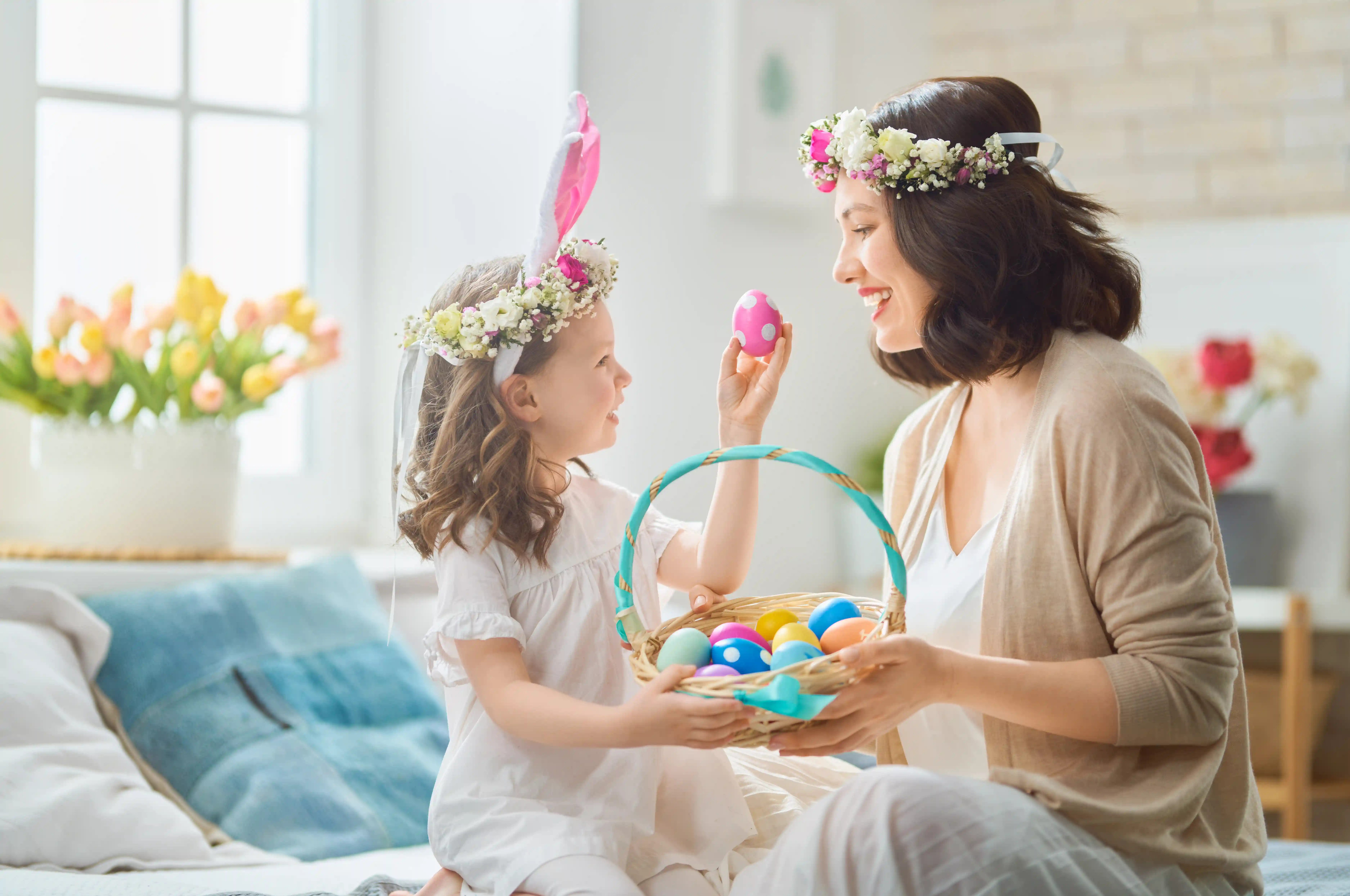 Mutter und Tochter mit Blumenkränzen und einem Korb in dem bemalte Eier sind